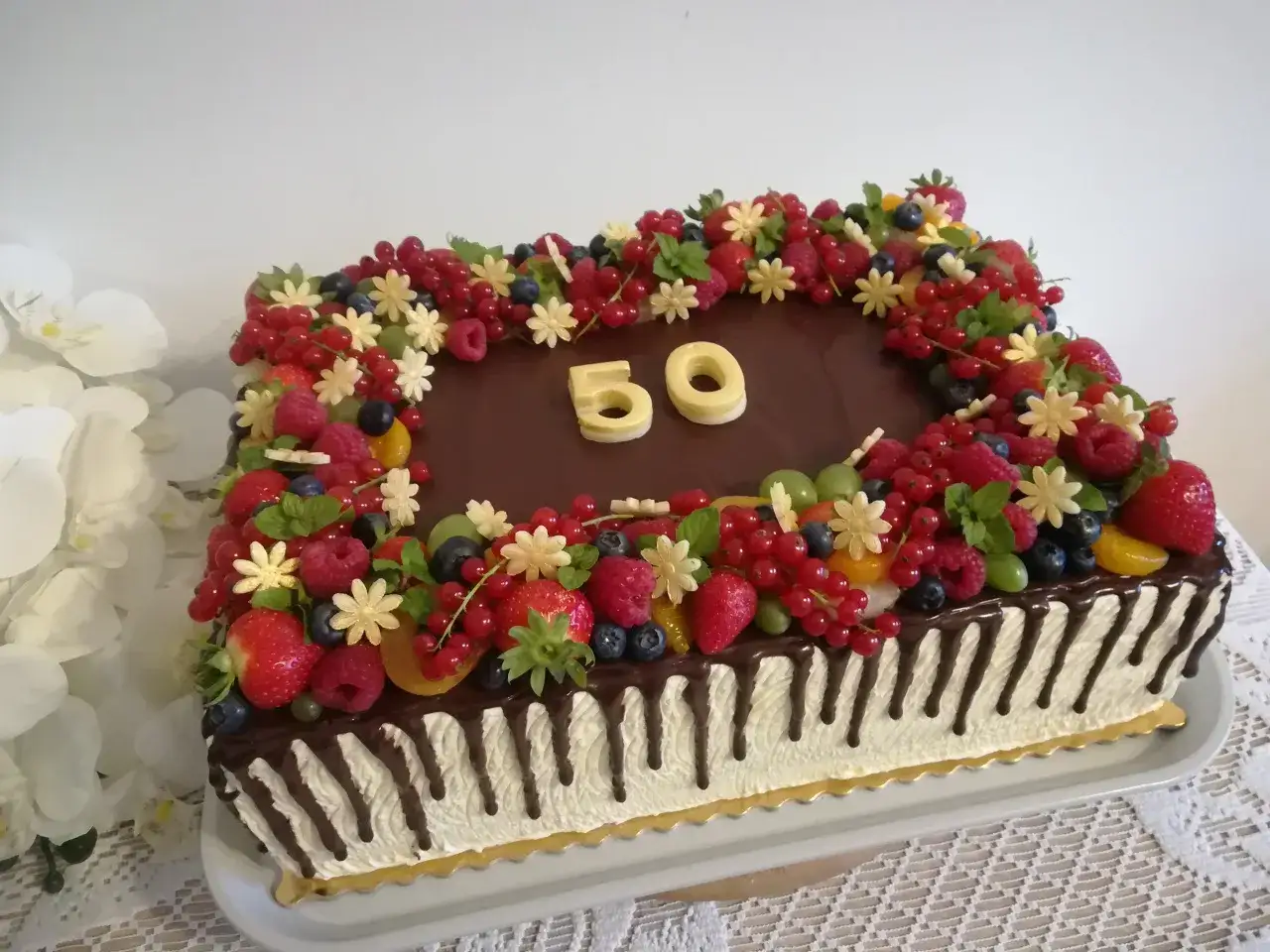 Elegancki tort prostokątny z czekoladą i bogactwem owoców: truskawki, maliny, borówki, porzeczki. Cyfry 