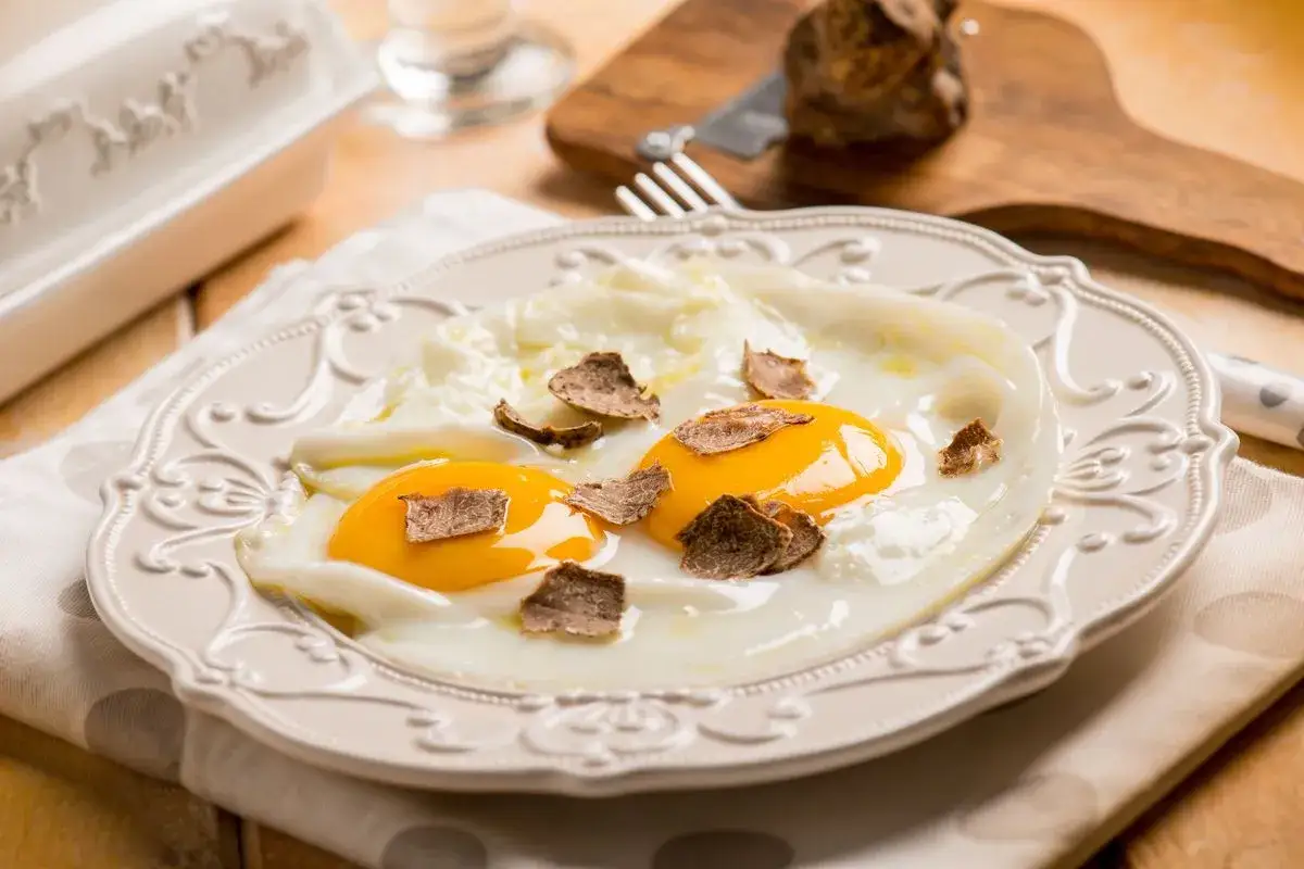 Uova al tegamino con scaglie di tartufo nero. Un'idea semplice per un piatto gourmet, perfetta per le tue ricette con formaggio al tartufo.