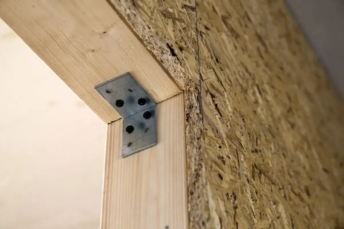 Metalowy kątownik wzmacnia drewnianą konstrukcję, gdzie tynk na OSB będzie tworzył ścianę.