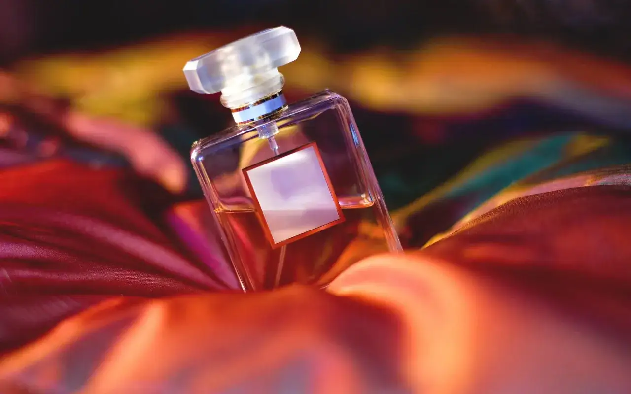 Elegancka butelka perfum na jedwabnej tkaninie. W jej wnętrzu kryją się aldehydy perfumy, obiecując luksusowy zapach.