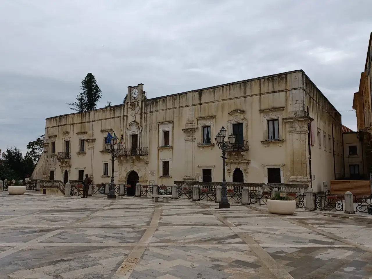Piazza di Santa Margherita Belice con il palazzo municipale, un orologio sulla facciata e un monumento.