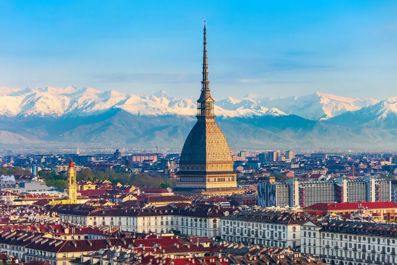 Panoramica di Torino con la Mole Antonelliana e le Alpi innevate sullo sfondo. Un invito a scoprire cosa vedere a Torino a piedi, tra tetti rossi e architetture storiche.