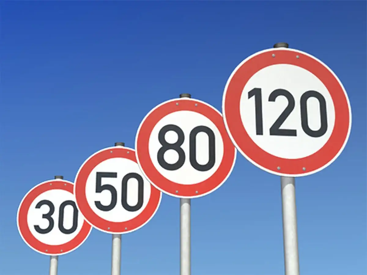 Vier runde Verkehrsschilder mit Geschwindigkeitsbegrenzungen (30, 50, 80, 120) vor blauem Himmel. Sie zeigen, wie schnell man auf der Autobahn fahren darf.