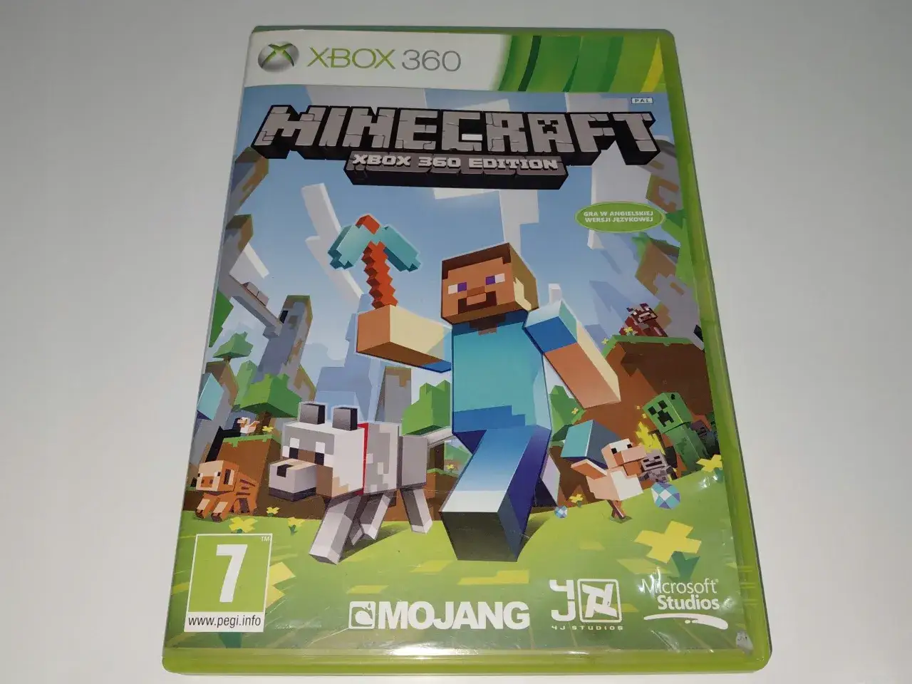 Minecraft na Xbox 360, idealna gra dla dzieci od 5 lat. Steve z kilofem, pies i inne postacie z gry.