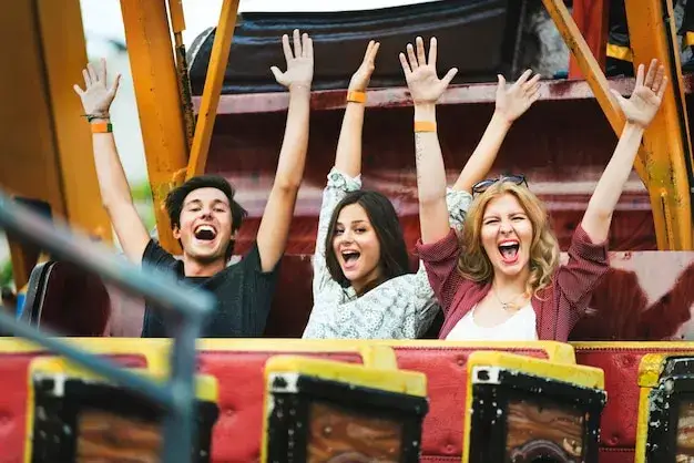 famille heureuse parc d'attractions vs groupe d'amis sur des montagnes russes