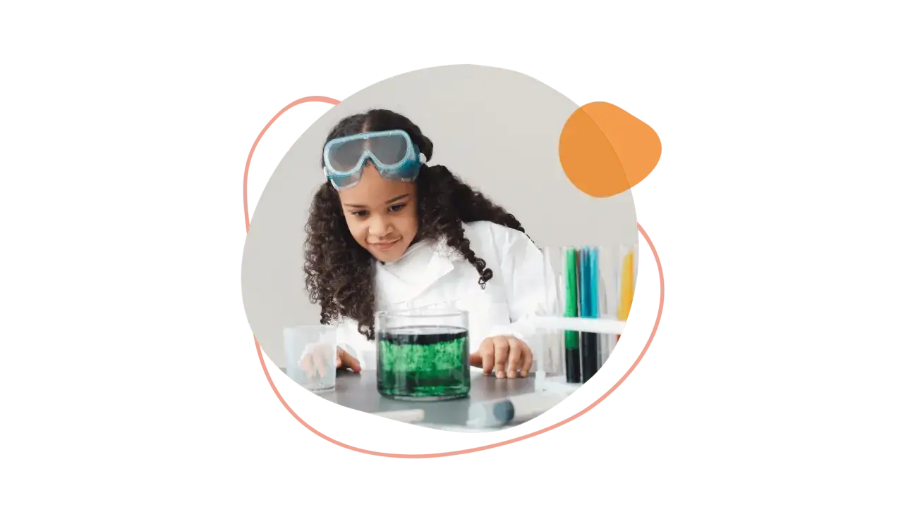 Ein kleines M&auml;dchen im Laborkittel und Schutzbrille experimentiert mit gr&uuml;ner Fl&uuml;ssigkeit. Sie ist fasziniert von den bunten Reagenzgl&auml;sern.
