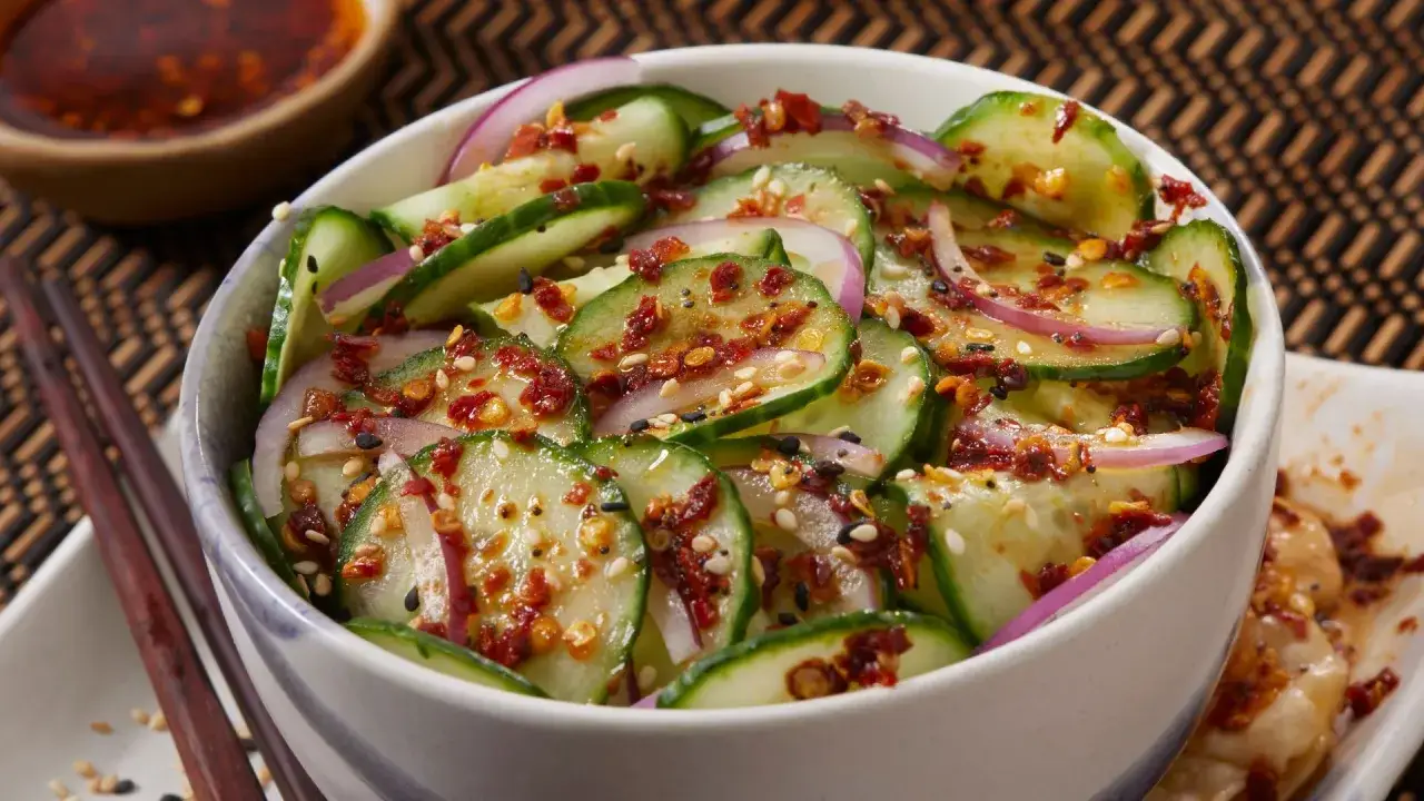 Frischer asiatischer Gurkensalat mit roten Zwiebeln, Sesam und Chili-Flocken. Ein leichter und würziger Genuss.