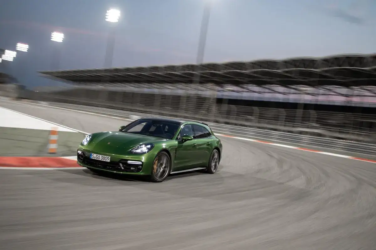 Zielony Porsche Panamera GTS na torze wyścigowym, dynamicznie pokonujący zakręt.