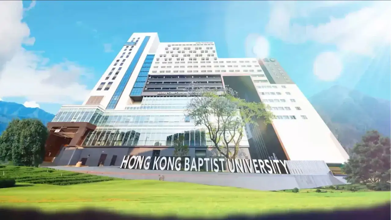 Le bâtiment moderne de la **Hong Kong Baptist University** se dresse sous un ciel bleu, entouré de verdure et de montagnes.
