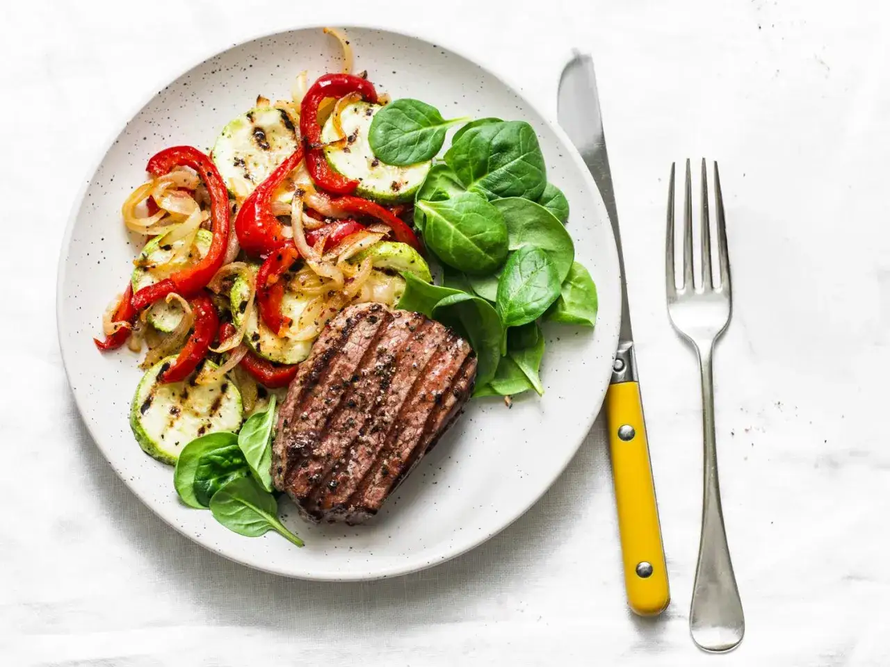 Grillowany stek z warzywami i świeżym szpinakiem. Posiłek idealny dla tych, którzy cenią sobie dietę lwa – sycącą i pełną białka.