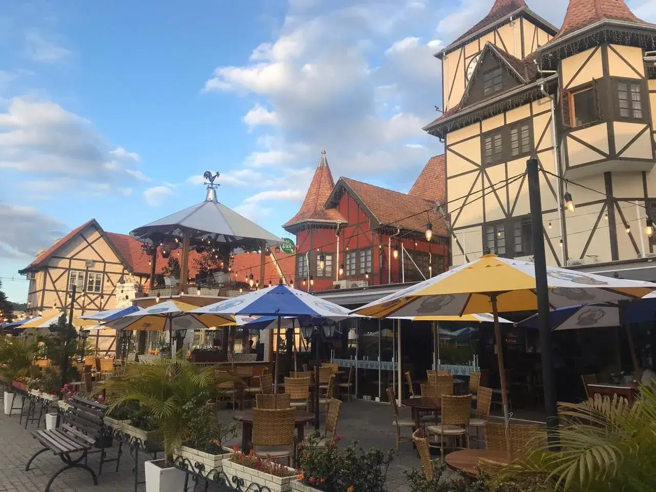 Bayerisch anmutende Gebäude mit Fachwerkkonstruktion und roten Dächern in Blumenau, Brasilien. Sonnenschirme und Tische laden zum Verweilen ein.