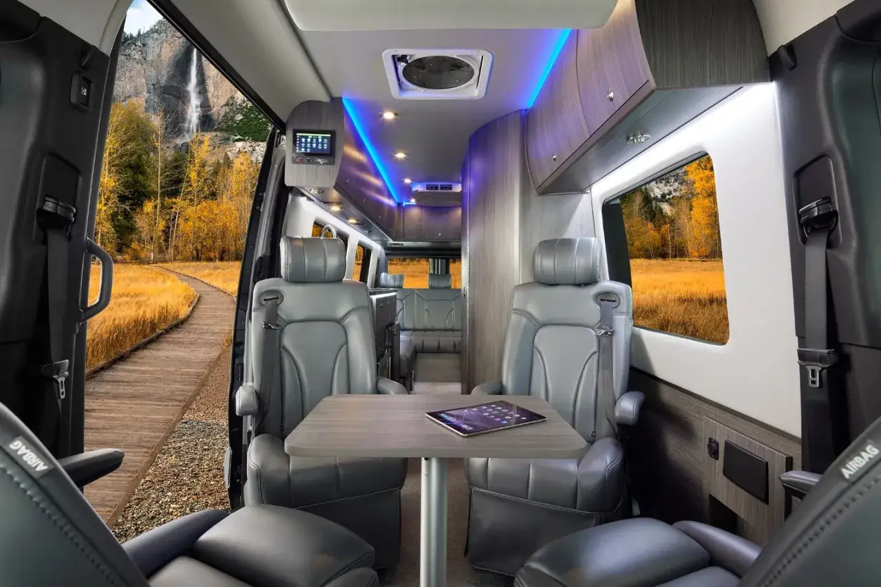 Intérieur luxueux d'un camping-car Pilote, avec sièges en cuir, éclairage d'ambiance et vue sur une cascade.