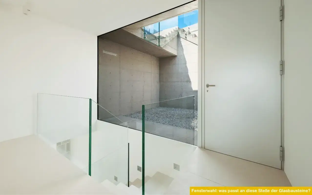 Moderne Treppe mit Glasgeländer, die eine Betonwand mit Kiesboden und Treppen im Freien freigibt. Eine gute Alternative, um Glasbausteine zu ersetzen.