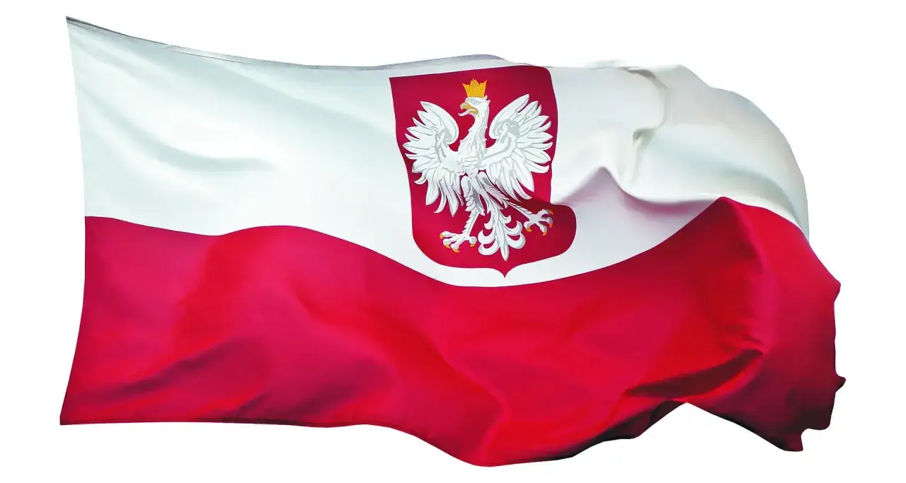 Flaga z orłem, biało-czerwona, dumnie powiewa na wietrze. Symbol Polski, orzeł w koronie, prezentuje się majestatycznie.