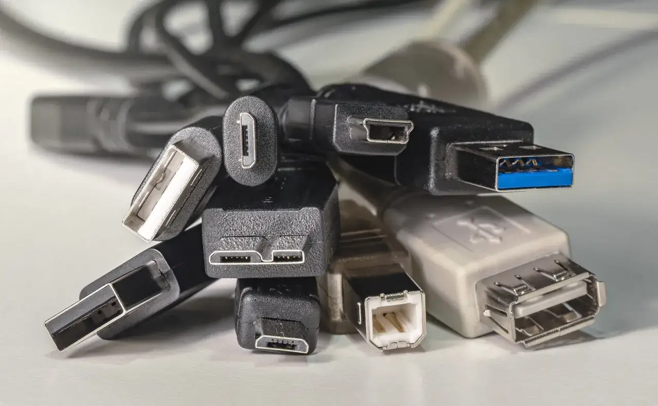 Plątanina kabli USB, w tym jeden z niebieskim złączem USB 3.2 Gen. 1, gotowa do podłączenia urządzeń.