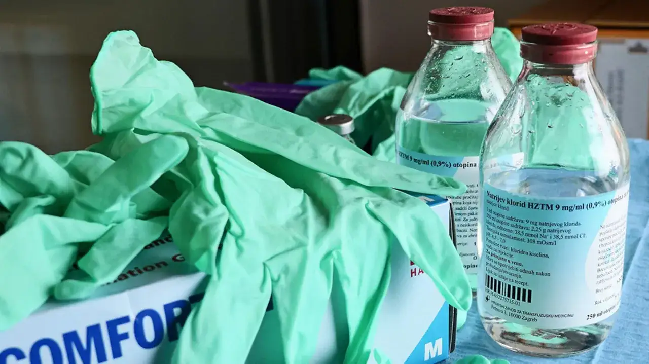 Grüne Einweghandschuhe und Infusionsflaschen, typische technische Pflegehilfsmittel für den medizinischen Einsatz.