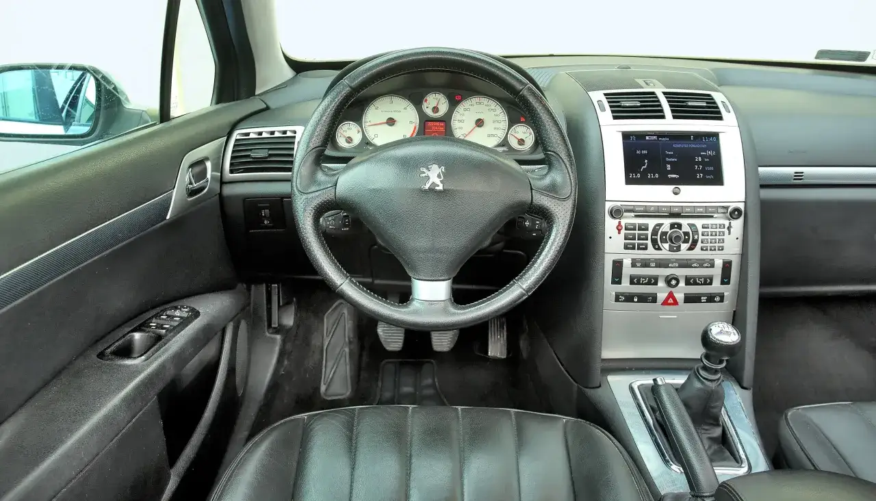 Wnętrze Peugeota 407, kierownica, deska rozdzielcza z komputerem pokładowym i ekranem multimediów. Wiele osób szuka peugeot 407 opinie.