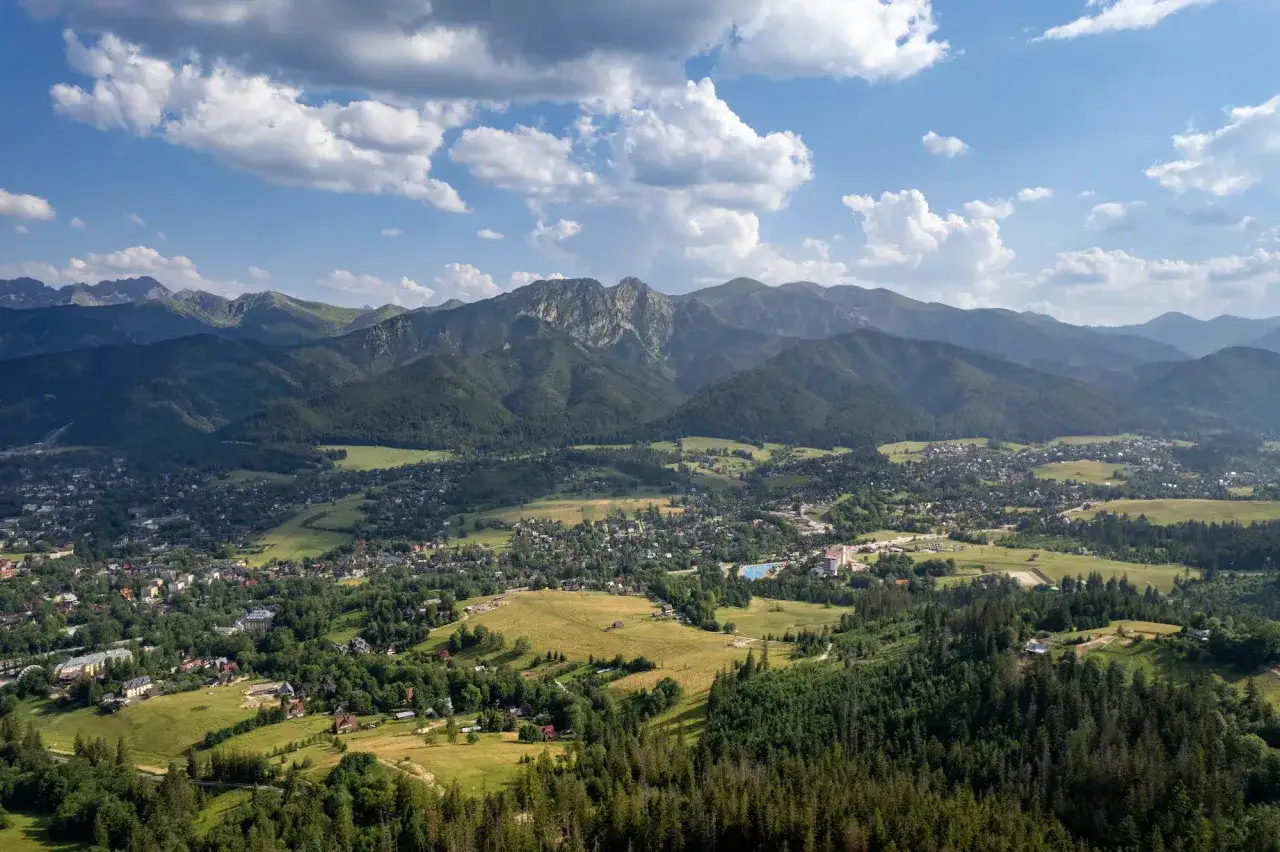 Widok na Zakopane i Tatry. Miasto rozciąga się u podnóża gór, oferując liczne atrakcje turystyczne.