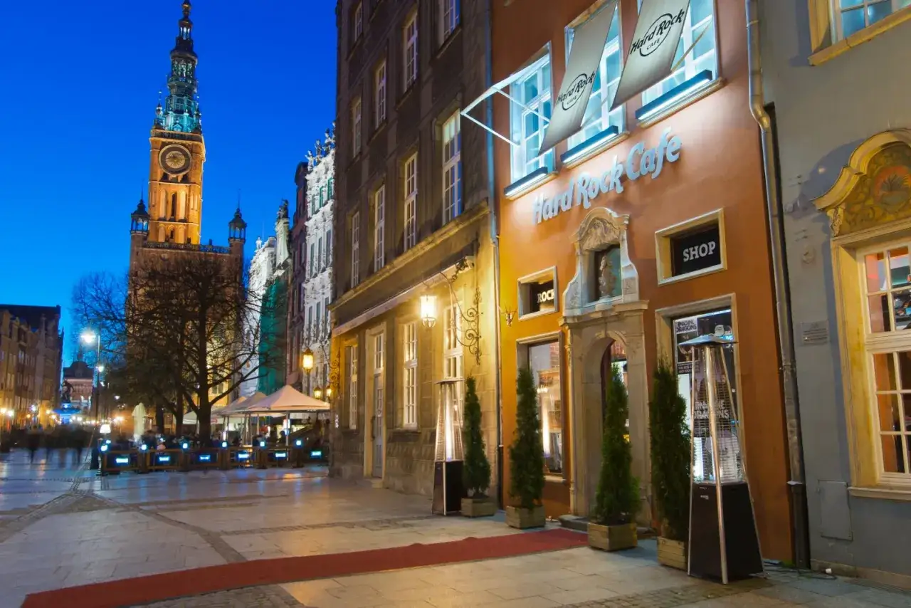 Wieczorny spacer po Gdańsku, z widokiem na wieżę Ratusza i wejście do Hard Rock Cafe.