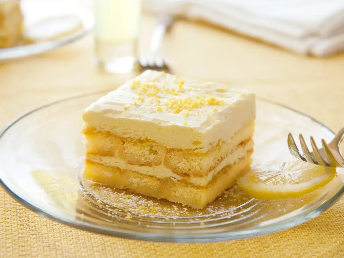 Ein Stück Limoncello Tiramisu auf einem Teller, garniert mit Zitronenschale.