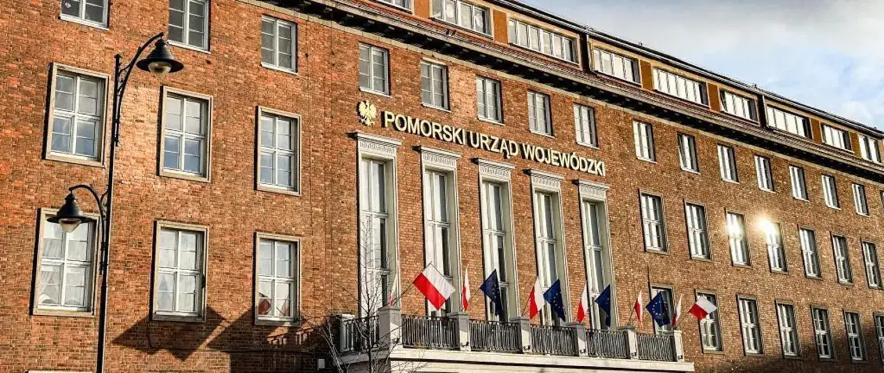 Pomorski Urząd Wojewódzki w Gdańsku, budynek z cegły z flagami.