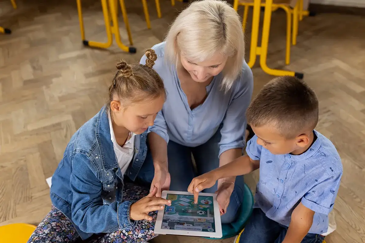 Nauczycielka pomaga dzieciom w nauce przez tablet. Dzieci w internecie uczą się przez zabawę, rozwijając swoje umiejętności.