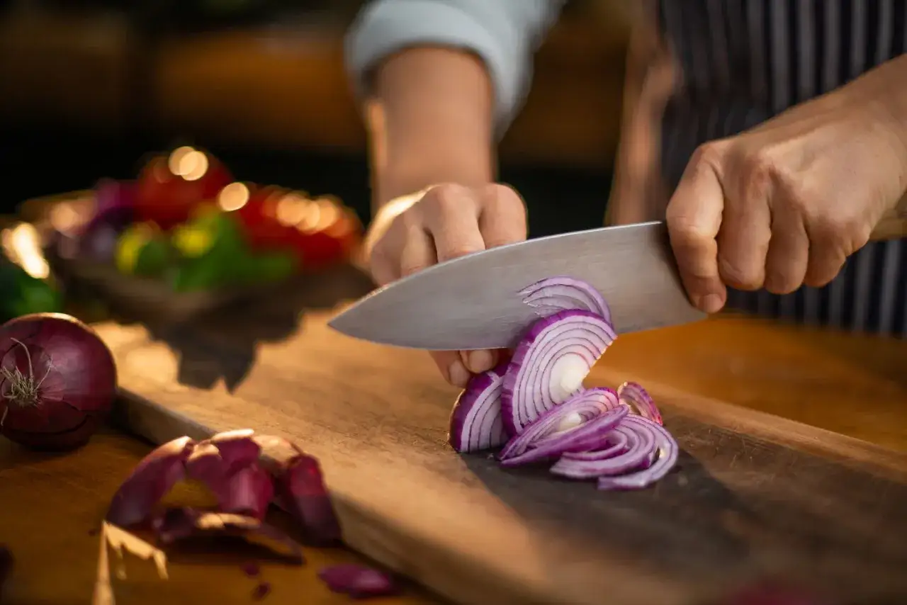 Rote Zwiebeln werden geschnitten, ein Beweis daf&uuml;r, wie gesund Zwiebeln sind. Sie sind eine wichtige Zutat f&uuml;r viele Gerichte.