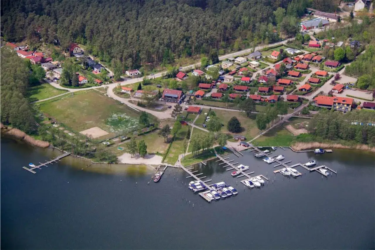 Luftaufnahme des J&auml;bscher Sees mit einem kleinen Dorf, einem Sportplatz und einem Yachthafen voller Boote.