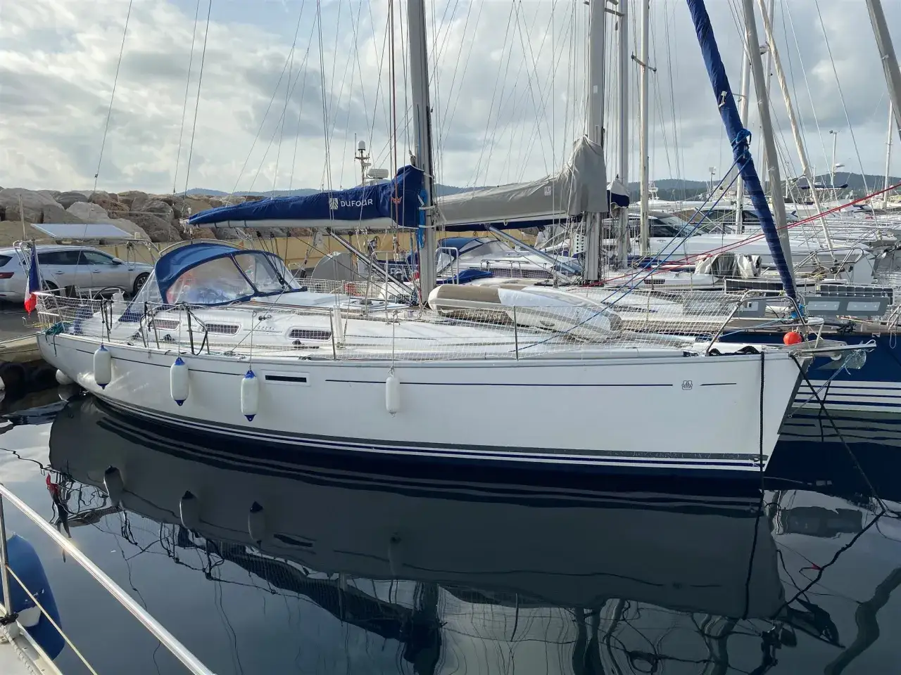 Un voilier Dufour 385 Grand Large à quai, reflet dans l'eau calme. Avis de propriétaires positifs pour ce modèle.