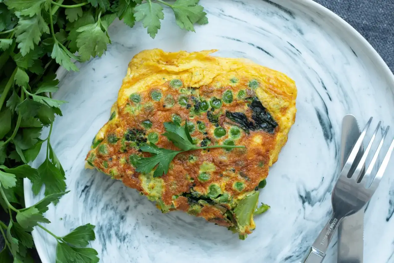 Une omelette aux petits pois et brocolis, garnie de persil frais. Une recette simple et savoureuse pour un repas léger.