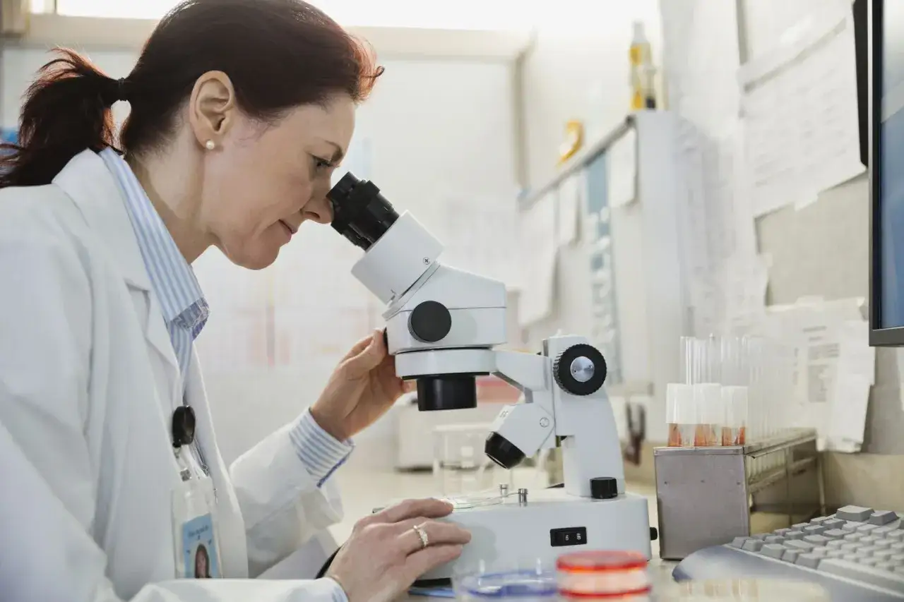 Naukowczyni analizuje próbki pod mikroskopem, kluczowy element w diagnostyce histopatologia.