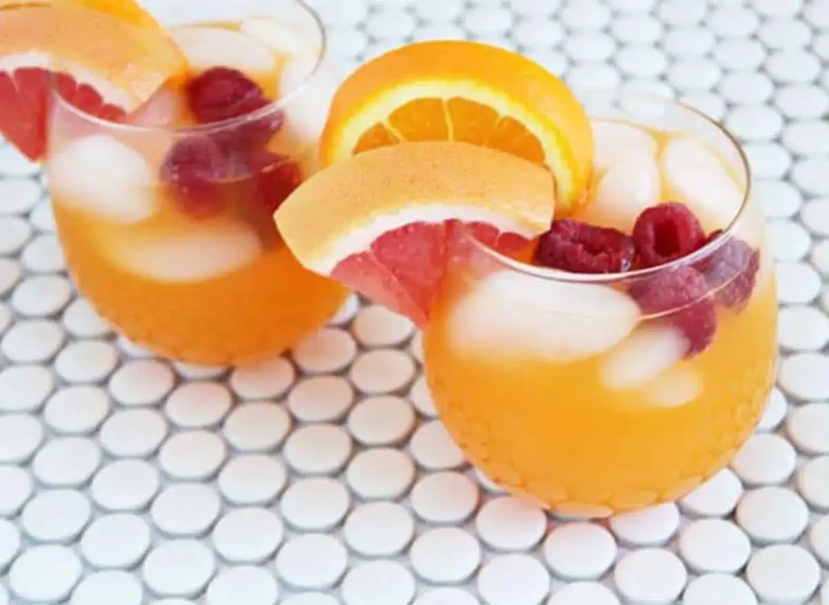 Zwei erfrischende Aperol Lillet Cocktails mit Himbeeren und Zitrusfr&uuml;chten auf einem Mosaik-Tisch.