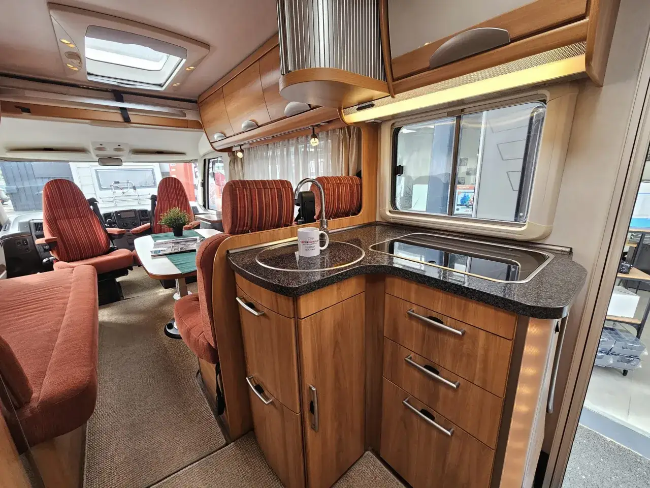 Int&eacute;rieur d'un camping-car Hymer B544, avec cuisine &eacute;quip&eacute;e, si&egrave;ges et table. Id&eacute;al pour consulter la fiche technique.