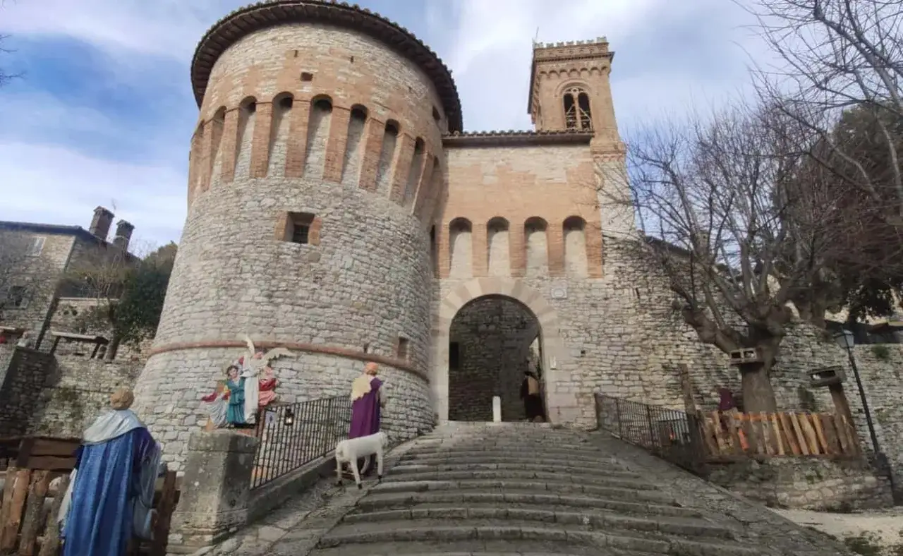 Presepe vivente a Corciano: cosa vedere. Antica porta medievale con statue e un agnello.