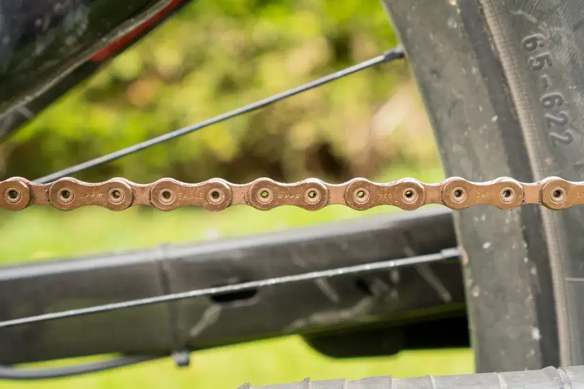Close-up of a SRAM Eagle xx1 chain, its copper-colored links showing the brand name and 