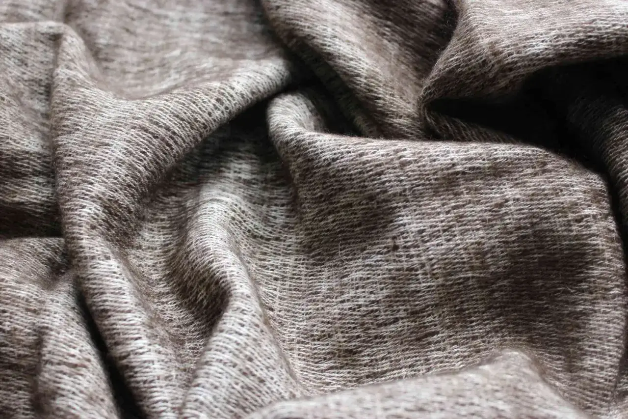 Miękka, brązowa wełna jaka, pofałdowana i lekko prześwitująca, tworzy ciepły, naturalny materiał.