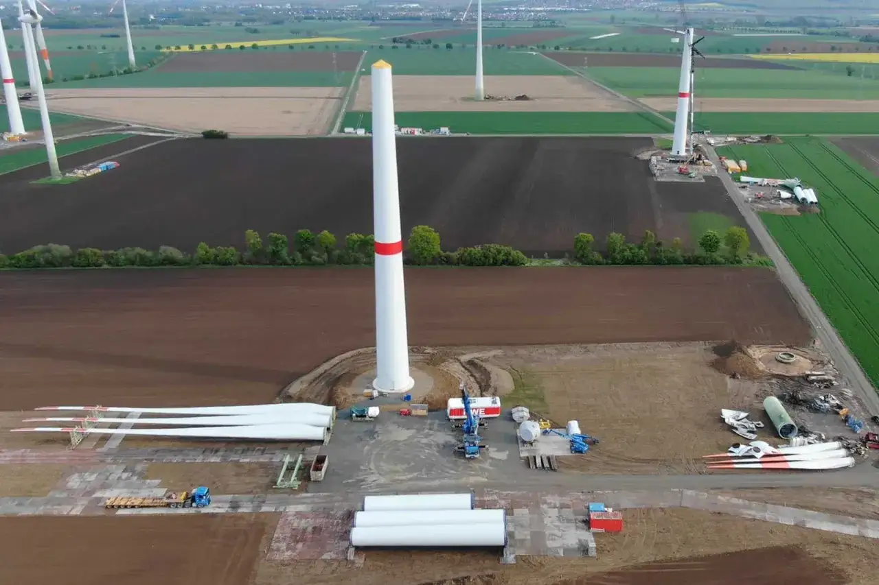 Baustelle f&uuml;r repowering von Windenergieanlagen. Neue T&uuml;rme und Rotorbl&auml;tter liegen bereit, w&auml;hrend alte Anlagen demontiert werden.
