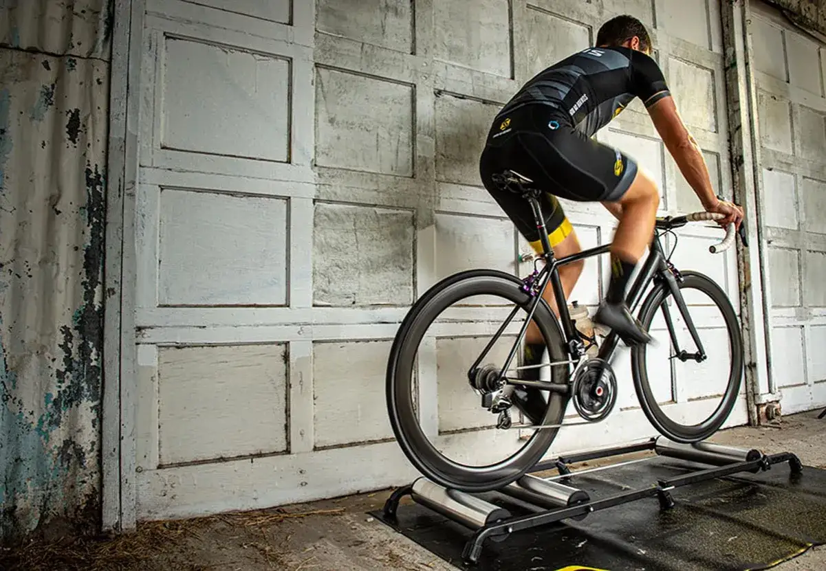 Cyclist training on bike rollers, a dynamic alternative to a trainer, against a weathered garage door.