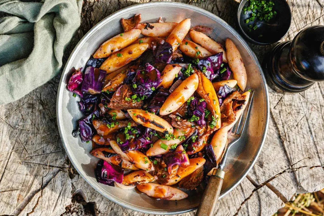 Schupfnudeln mit Rotkohl, ein herzhaftes Gericht, das auf einem rustikalen Holztisch serviert wird.