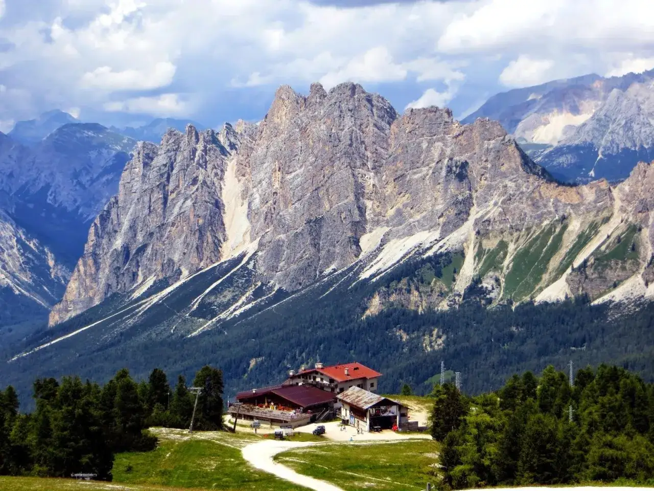 Rifugio alpino in un paesaggio mozzafiato, tra le localit&agrave; di montagna pi&ugrave; belle in estate. Cime rocciose imponenti, boschi verdi e cielo azzurro.