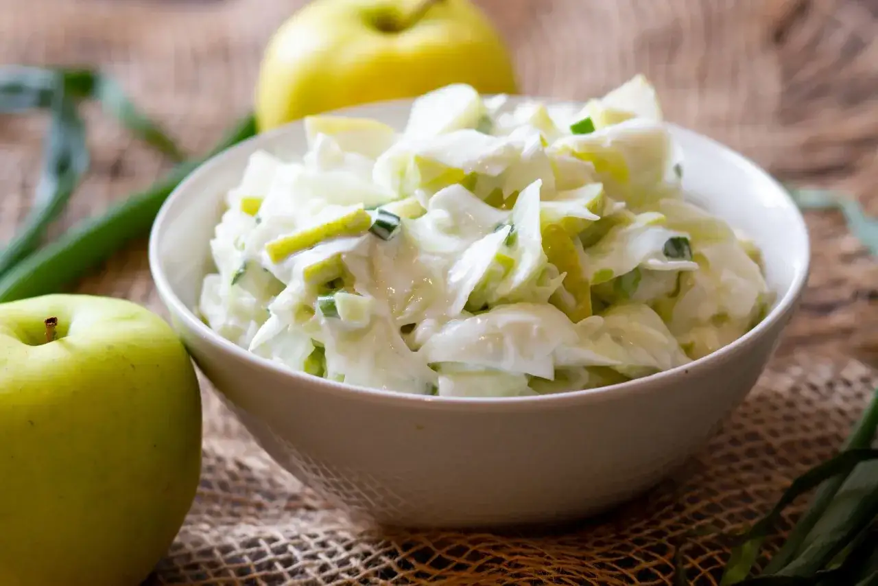 Ein cremiger Kohlrabi-Salat mit Apfelst&uuml;cken und Fr&uuml;hlingszwiebeln, garniert mit gr&uuml;nen &Auml;pfeln und Lauch.