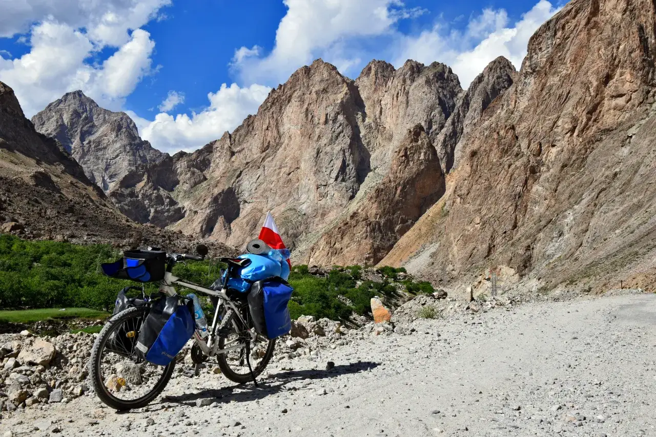 Rower z sakwami i polską flagą na tle gór Pamiru. Kluczowe wskazówki, jak zaplanować logistykę wyprawy rowerowej przez Pamir Highway.