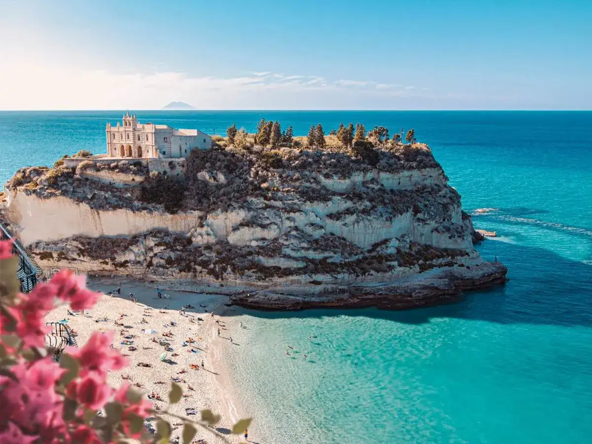 Spiagge Tropea: un santuario su uno sperone roccioso domina la sabbia dorata e il mare cristallino.