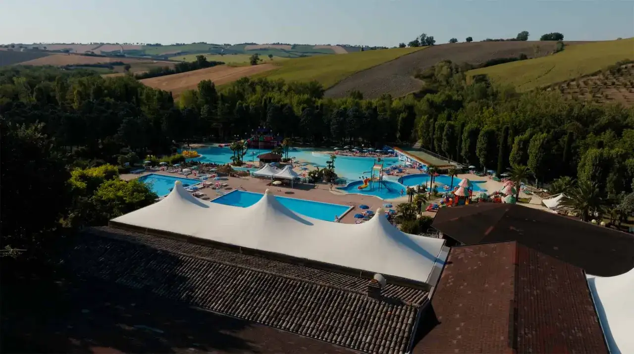 Vasta area del parco acquatico Cingoli con piscine, scivoli e aree relax, circondata da colline verdi.