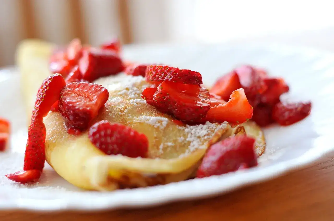 Deliziose crepes con farina di riso, guarnite con fragole fresche e una spolverata di zucchero a velo. Un dolce leggero e gustoso.