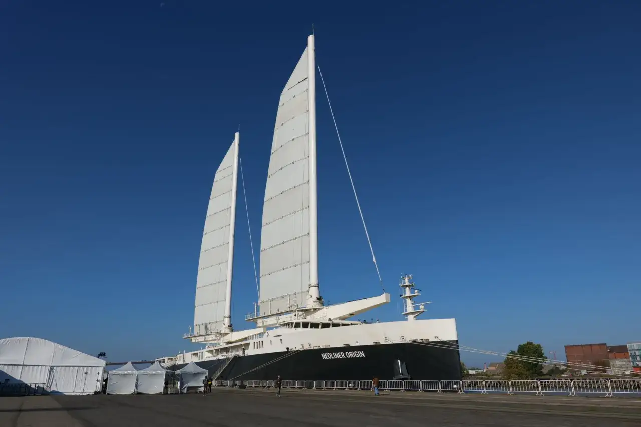 Le Neoliner Origin, un navire futuriste pour le transport à la voile, se dresse fièrement sous un ciel bleu éclatant.