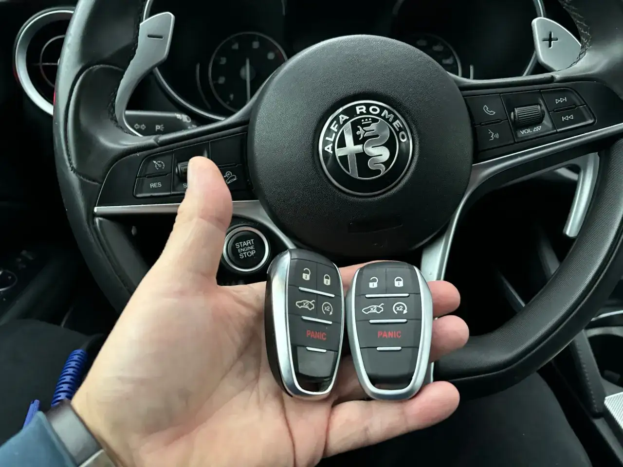 Dwa kluczyki samochodowe Alfa Romeo w dłoni, pytanie brzmi: ile kosztuje kodowanie kluczyka?