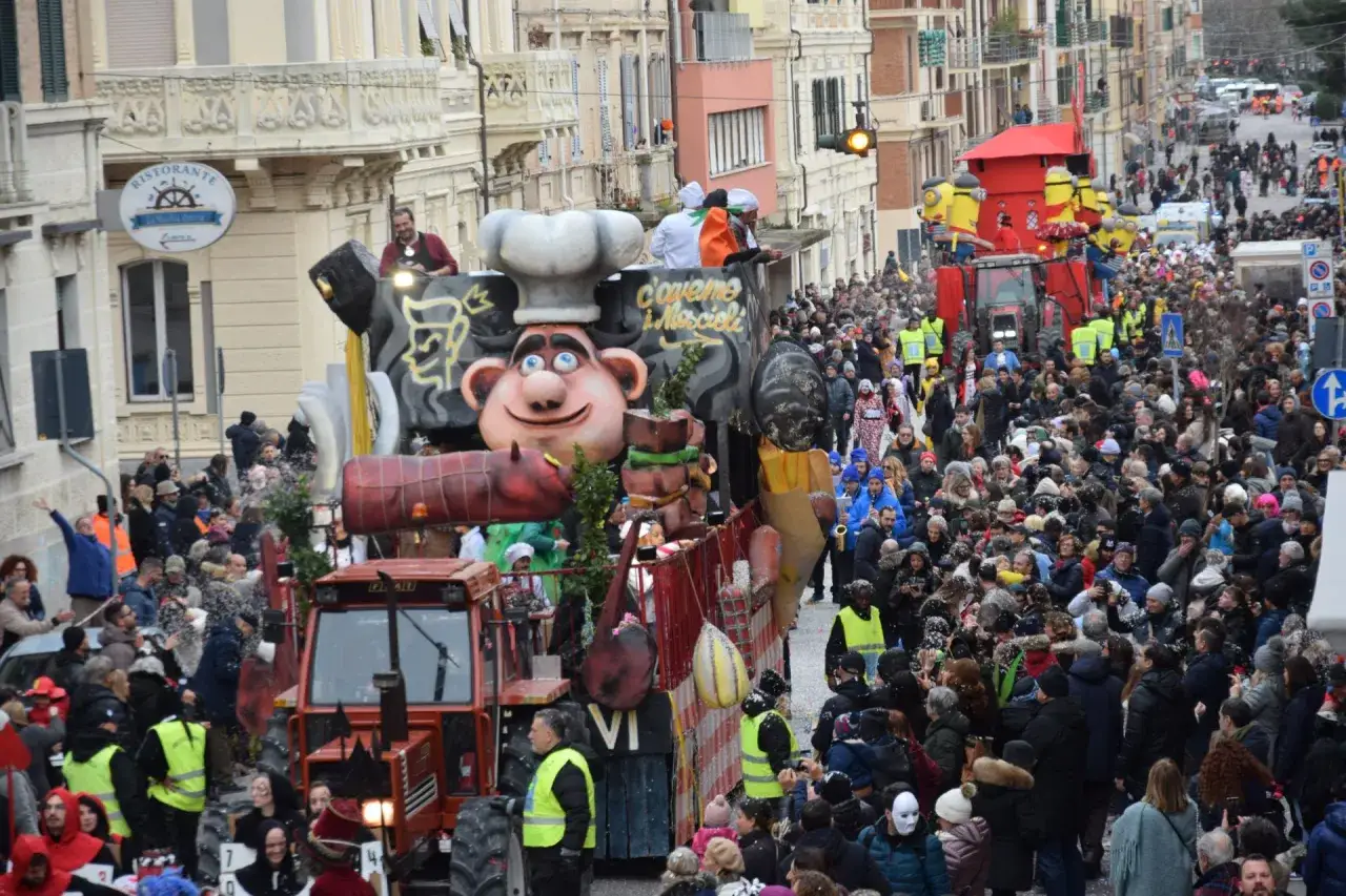 Carro allegorico con Minions e un gigante chef al carnevale di Ancona. Folla festante in strada.