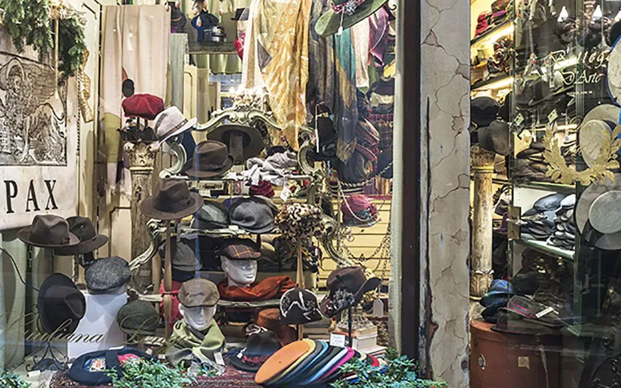 Vetrine di negozi a Venezia piene di cappelli eleganti e sciarpe colorate, un'esplosione di stile.