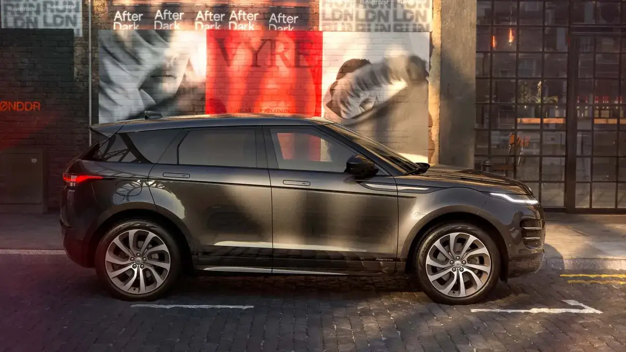 Dunkelgrauer Range Rover Evoque parkt vor einer Ziegelwand mit Plakaten in London.